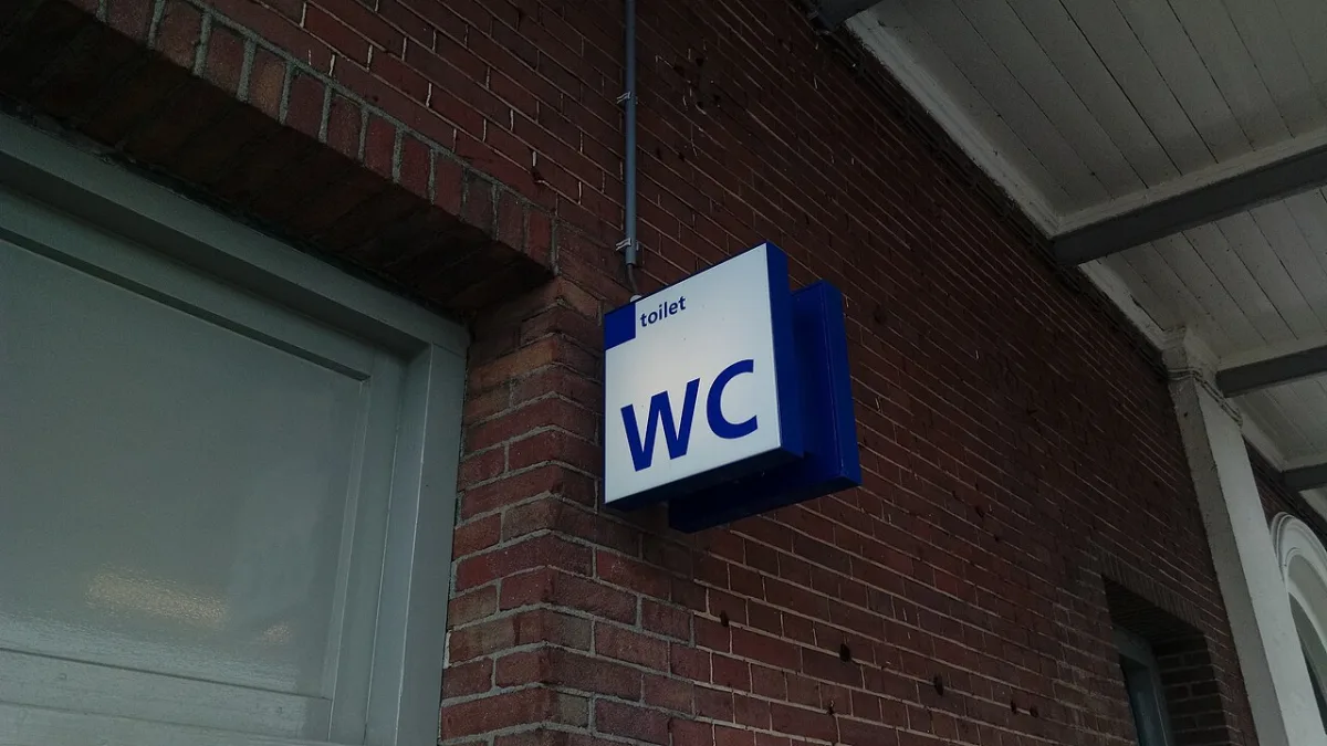 Blauw-wit verlicht WC-bord aan een bakstenen muur