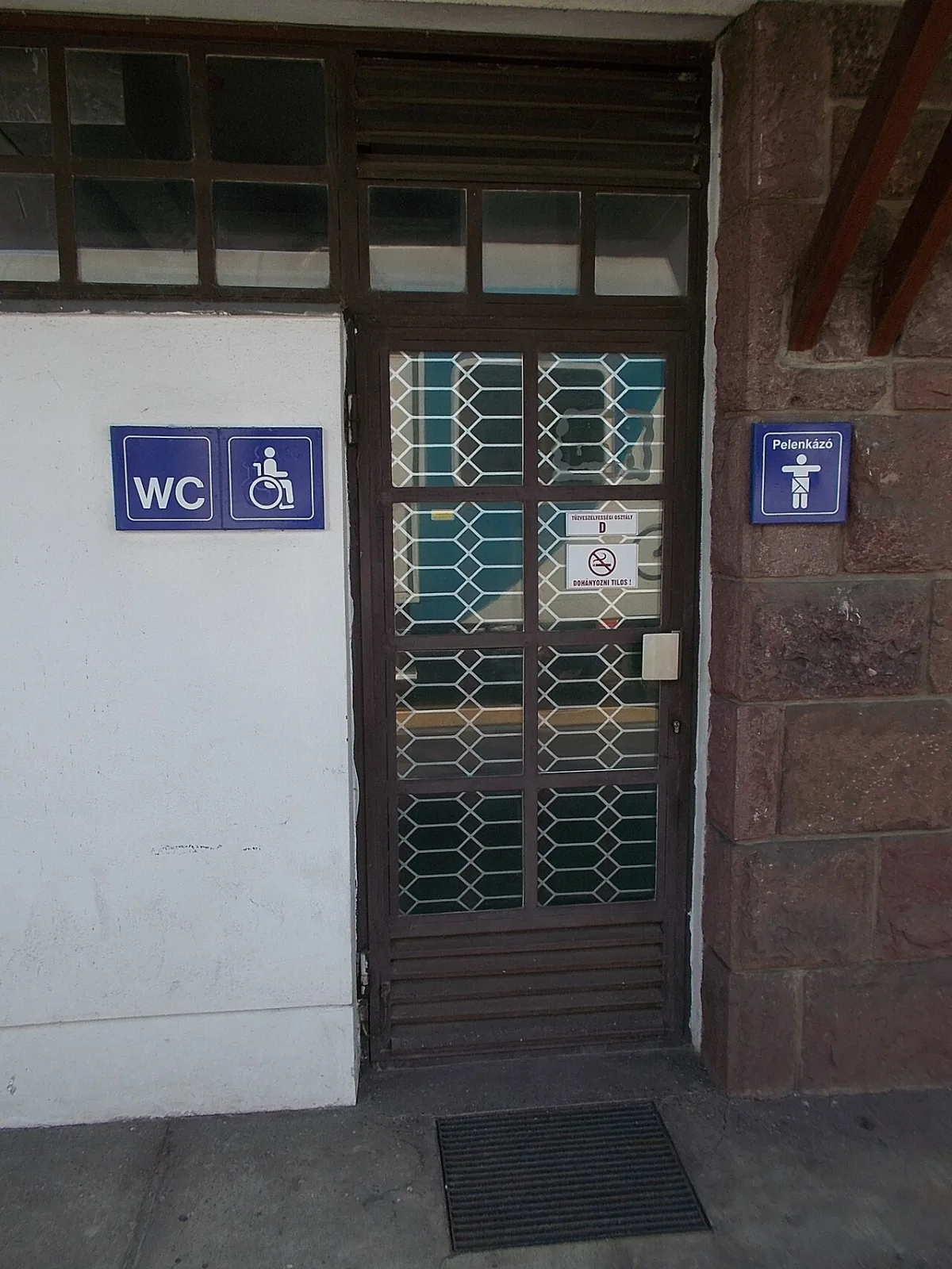 Blauwe bordjes bij een toiletingang: WC met rolstoelsymbool en daarnaast een verschoonruimte